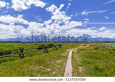 split rail fence and path with alpine mountains as a backdrop
