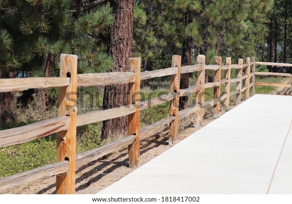 split rail fence wooden wood three 3 high next\
to sidewalk