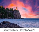 The Split Rock lighthouse at the edge of a waterside cliff under the orange and blue shaded sunset sky