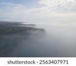 Split Rock Lighthouse stands on a misty cliff, surrounded by dense forest and a dramatic coastal view 