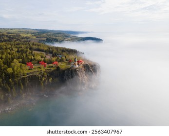 Split Rock Lighthouse stands on a misty cliff, surrounded by dense forest and a dramatic coastal view 