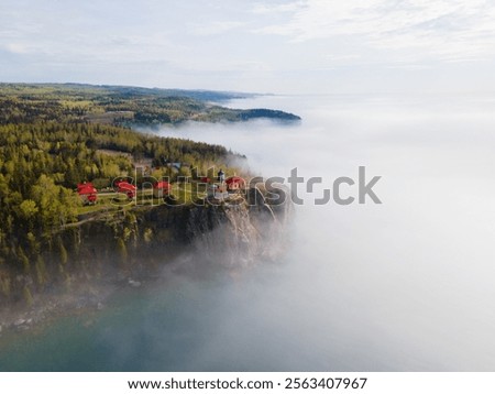 Split Rock Lighthouse stands on a misty cliff, surrounded by dense forest and a dramatic coastal view 