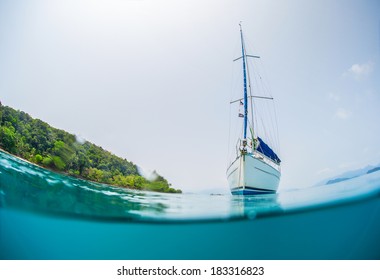 Split shot of anchored sail boat near green island and clear underwater - Powered by Shutterstock