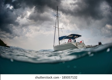 Split shot of anchored sail boat with heavy clouds in sky