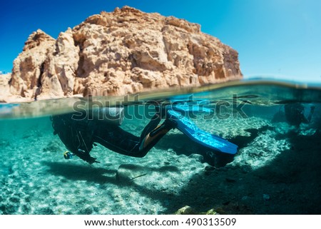 Similar – Unbekannter Jugendlicher in Neoprenanzug und Schnorchel im klaren Wasser mit felsigen Klippen von Menorca, Spanien, geteilter Blick über und unter der Wasseroberfläche