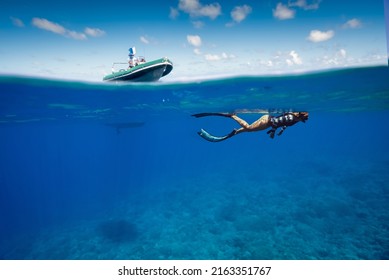 Split Shot Of Snorkeler Swimming At The Surface Of A Tropical Coral Reef With A Super Yacht Tender Above For Safety On A Sunny Day With Clear Waters In Fakarava Atoll, French Polyesia