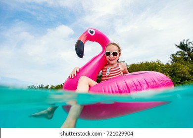 Split underwater photo of adorable little girl with pink flamingo inflatable ring swimming in a tropical ocean on summer vacation