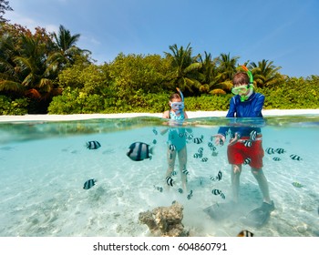 Split Underwater Photo Of Kids Having Fun In Ocean Enjoying Snorkeling With Tropical Fish