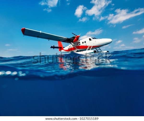 Split\
underwater photo of small seaplane on\
water