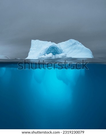 Split view of an iceberg showing above and below the water line. Underwater iceberg. Antarctica. Arctic Greenland. Climate change and global warming travel concept.