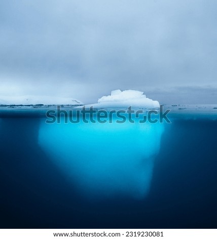 Split view of an iceberg showing above and below the water line. Underwater iceberg. Antarctica. Arctic Greenland. Climate change and global warming travel concept.