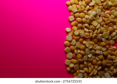 Split yellow peas placed to the side on a vibrant pink background, creating a stylish color contrast and copy space. This textured composition is perfect for culinary layouts, grocery advertisements, and illustrations of a vegetarian diet.