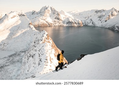 Splitboarder standing on his splitboard in the foreground and admiring the beauty of mountain range