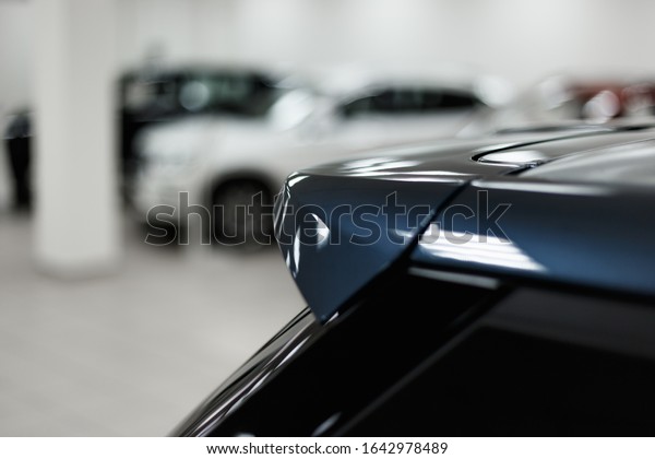 The spoiler of the car. The\
background is blurred. Classic blue color. Car detail. Exterior\
detail
