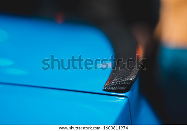 Spoiler on the trunk of a\
blue car.