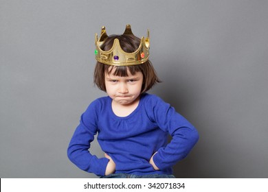 spoilt kid concept - adorable preschool child with golden crown on head putting hands on hips for confident mollycoddled little king or queen metaphor,studio shot