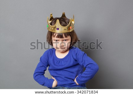 spoilt kid concept - adorable preschool child with golden crown on head putting hands on hips for confident mollycoddled little king or queen metaphor,studio shot