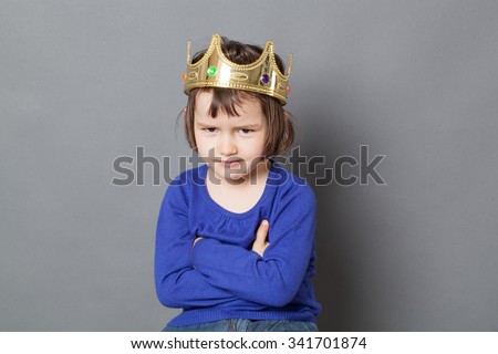 spoilt kid concept - smiling 4-year old child with messy hair and golden crown on head sitting with arms crossed for mollycoddled metaphor,studio shot