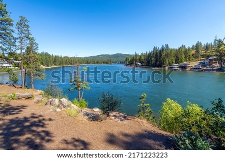 The Spokane River in Post Falls, Idaho, with waterfront homes along the shore near Black Bay park on a summer day.
