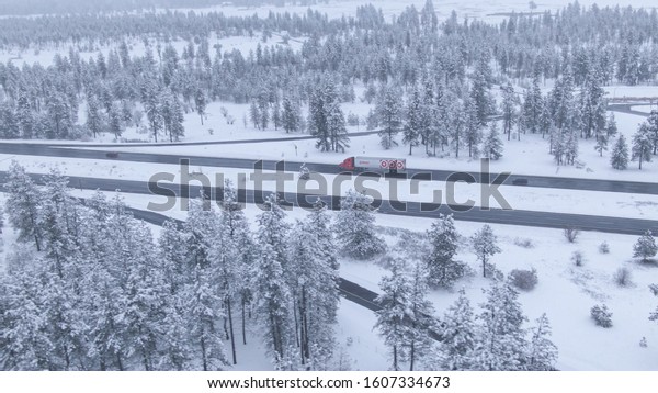 SPOKANE, WASHINGTON, UNITED STATES OF AMERICA,\
MARCH 2013: AERIAL: Big Target truck hauls a heavy container along\
a dangerous icy highway. Freight truck speeds along a wet freeway\
during a snowstorm.
