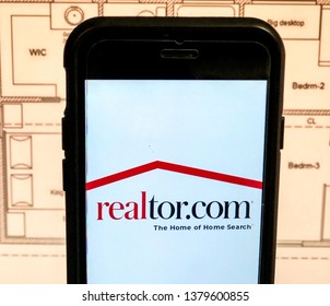 Spokane, WA/USA - April, 2019: View Of Realtor.com App Open On A Smart Phone. House Floor Plan Is Visible In The Background. Realtor.com Is A Real Estate Listings Website.