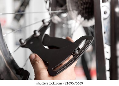 Spoke tension meter uses mechanic to accurately measure tension of each spoke in wheel. In hand of a bicycle repairman there is a strain gauge that checks the tension of the spokes of a mountain bike
