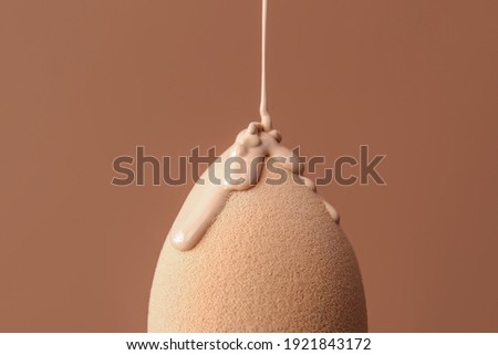 Sponge with foundation for makeup on color background