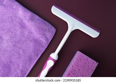 Sponge, Rag And Glass Scraper For Cleaning On A Purple Background