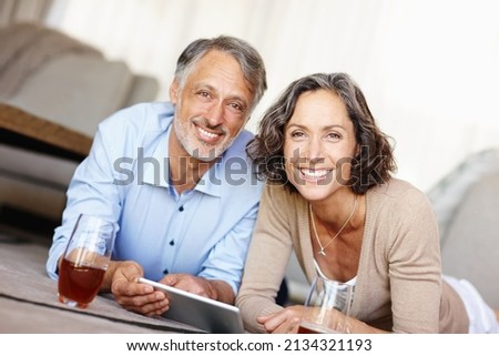 Spontaneity is the spice of life. Portrait of a happy mature couple lying on the floor and using a digital tablet.