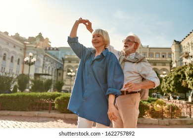 Spontaneous Dance. Portrait Of Happy Seniour Couple Smiling While Dancing Together Outdoors