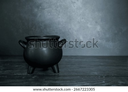 Spooky black empty cauldron on dark backdrop
