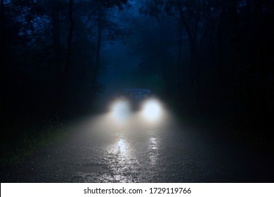 A Spooky Forest Road With Car Headlights Shining Through The Fog.