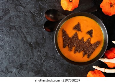 Spooky Halloween Pumpkin Soup With Jack O Lantern Face. Top View Table Scene On A Black Background.