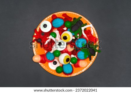 Spooky Halloween Treats: Jelly Finger Candies, Eyeballs, Spiders, and Brain Sweets on black Background. Top view