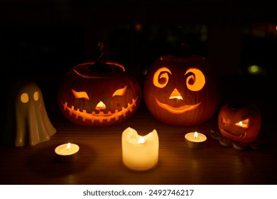 Spooky season halloween decor. Carved pumpkins by miniature ghost and child Jack-o'-lantern with candles - Powered by Shutterstock