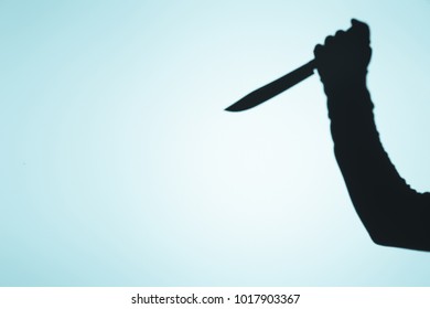 Spooky Shadow Of Person Holding Knife In Hand On Blue