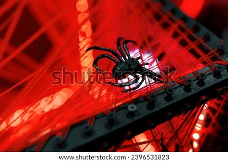 A spooky spider decoration on a web-covered bridge with red lighting