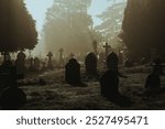 A spooky Victorian graveyard. With graves silhouetted by fog on a mysterious creepy winters night.