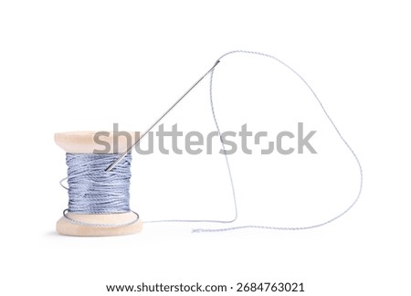 Spool of light blue thread with needle isolated on white