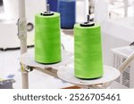 Spool of thread on an industrial sewing machine in a garment factory, industrial textile background, sewing factory, clothing manufacturing