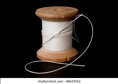 Spool Of White Thread And A Needle Over A Black Background