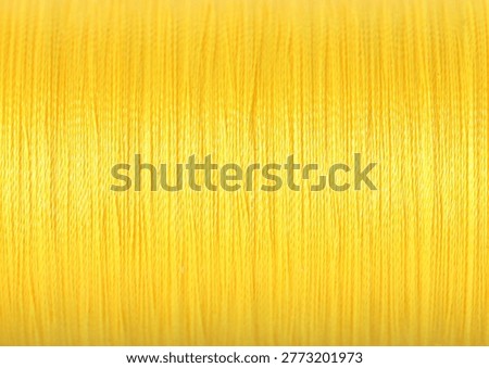 Spool of yellow sewing thread as background, closeup