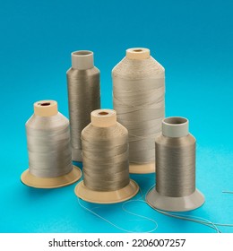 Spools Of Beige Polyester Thread On A Blue Background