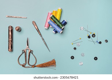 spools of colored thread on a smooth blue surface along with vintage sewing objects