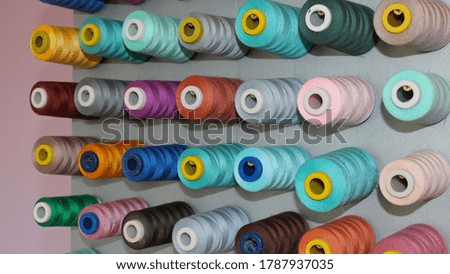 Spools of colored thread on a vertical stand. Sewing studio. 