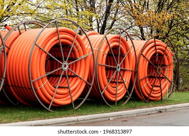 Spools of orange fiber optic conduit on a mobile reel for fiber optic cable installation