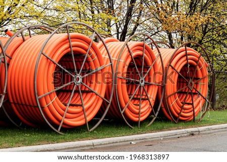 Spools of orange fiber optic conduit on a mobile reel for fiber optic cable installation