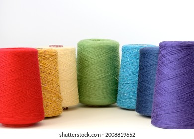 Spools of rainbow colors wool yarn for hand and machine knitting on a white background