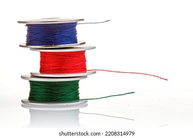 spools of thread in blue, red, green colors on a white background close-up