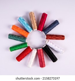 Spools of thread for sewing in different colors on white background. Round, sun like shape.